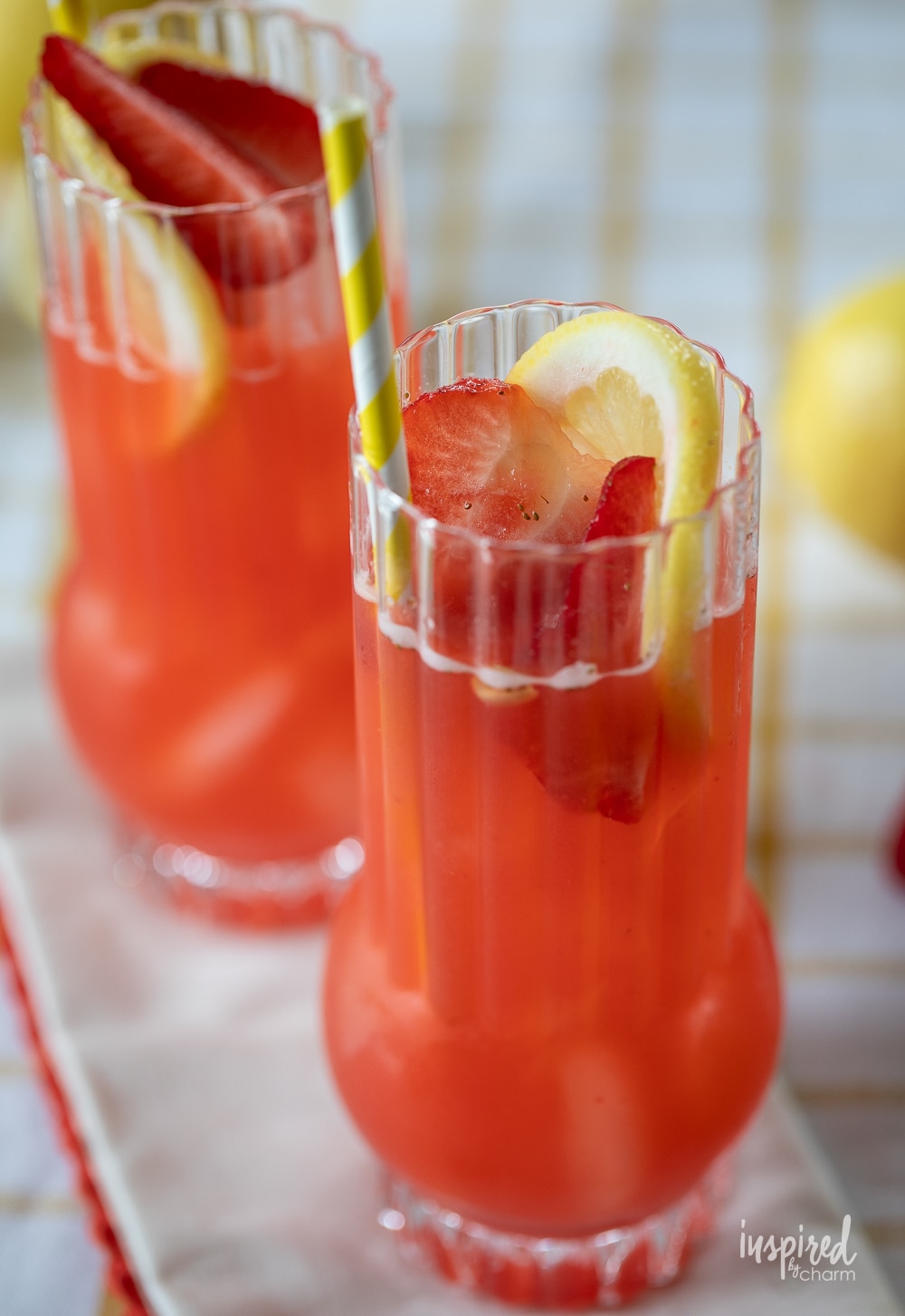 two Strawberry Lemonade Vodka Cocktail with straws and lemon garnish.
