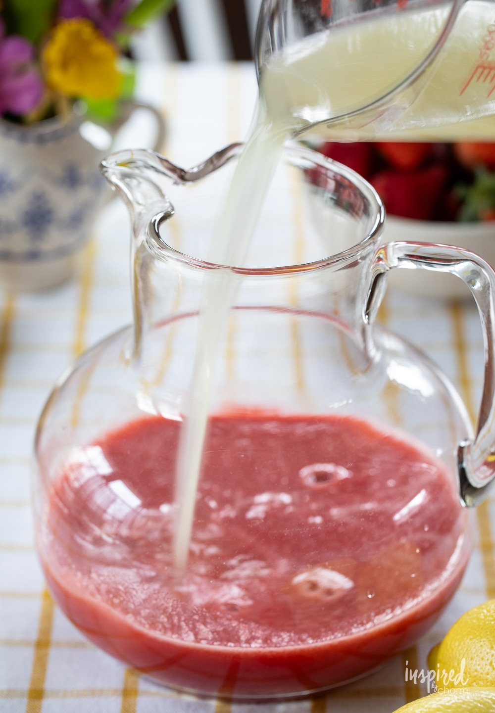 adding lemon juice to a pitcher of strawberry juice.