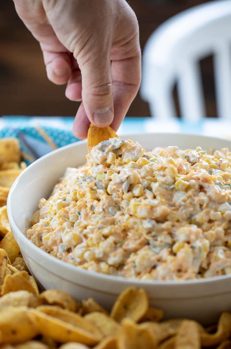 hand dipping into corn dip in a bowl.