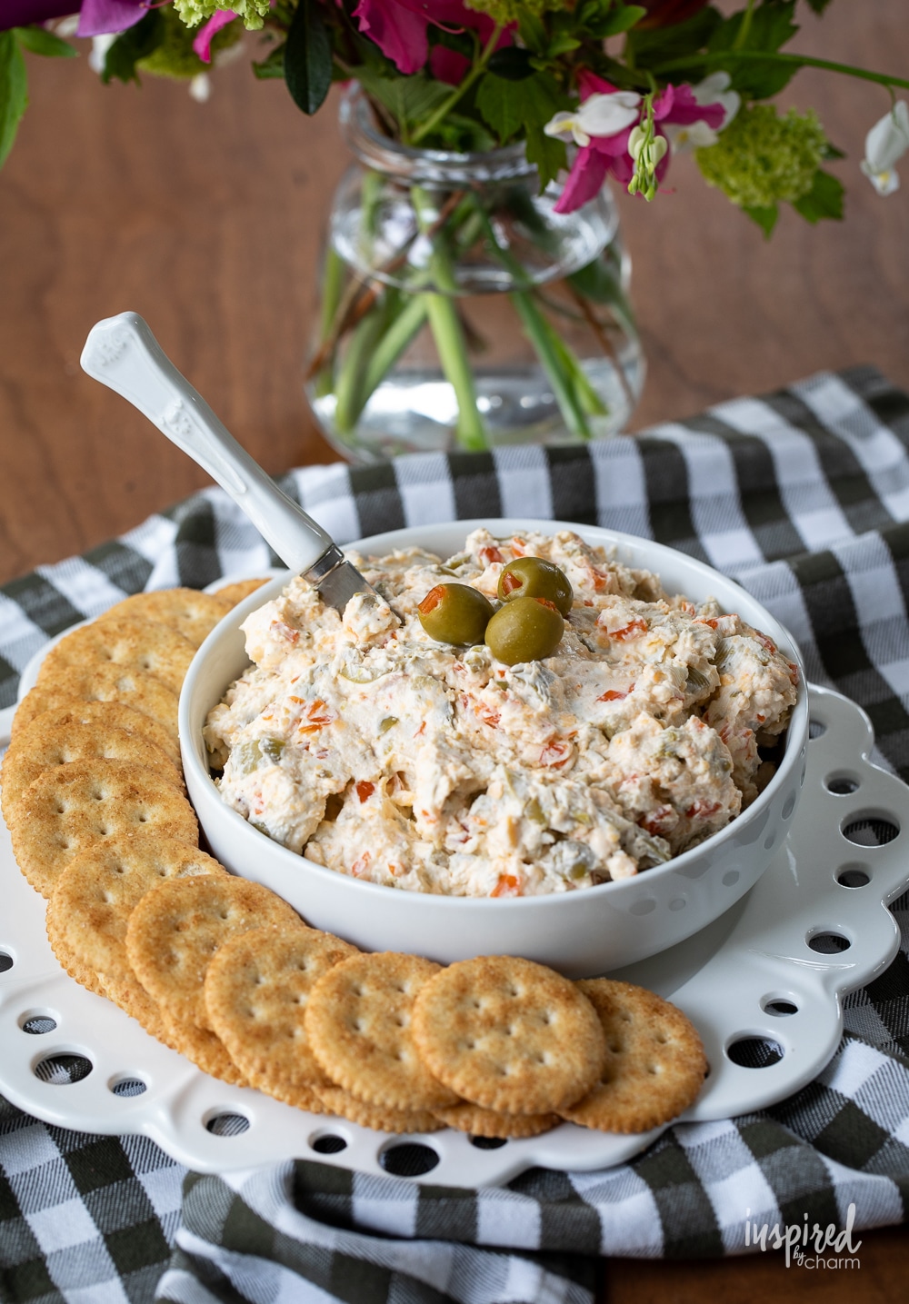 bowl filled with olive dips on a plate with crackers.