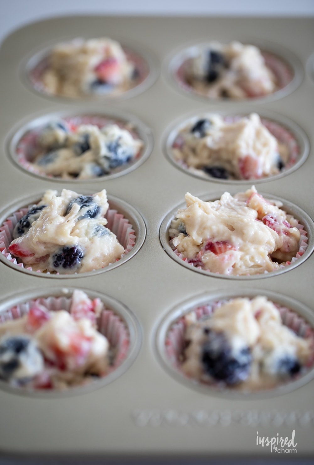 unbaked triple berry muffins in a muffin pan.