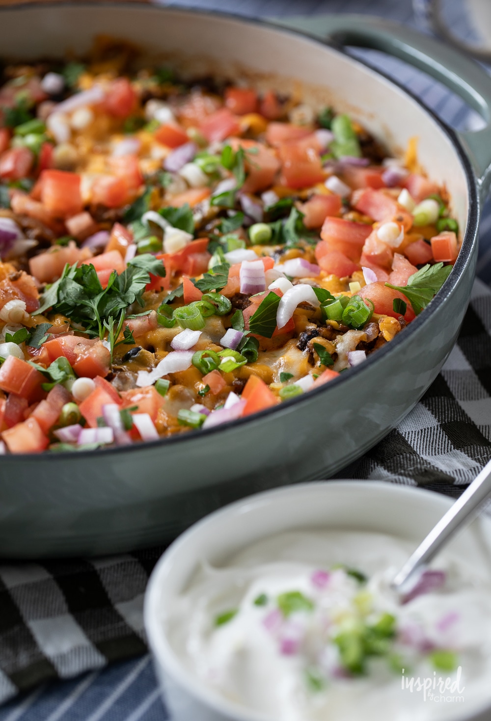 easy hot taco dip in a skillet with a bowl of sour cream on the side. 