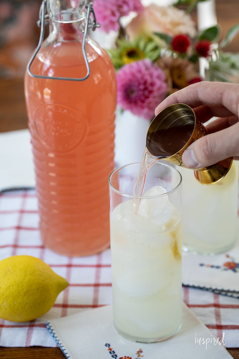 adding a shot of homemade rhubarb ginger vodka into lemonade.
