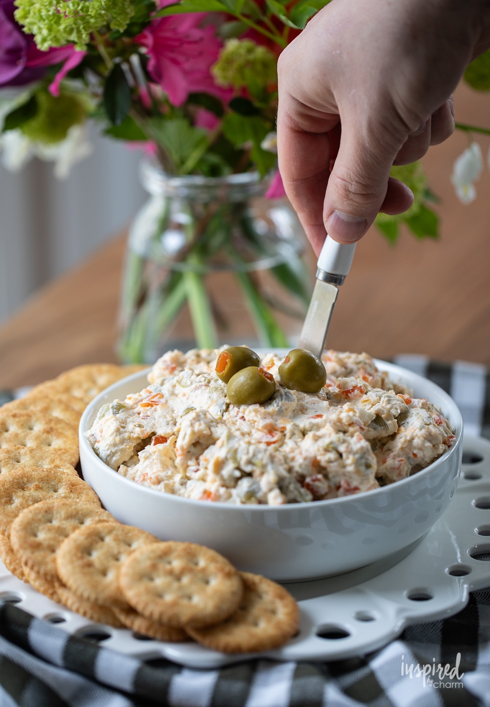 hand with spreading taking olive dip from bowl.