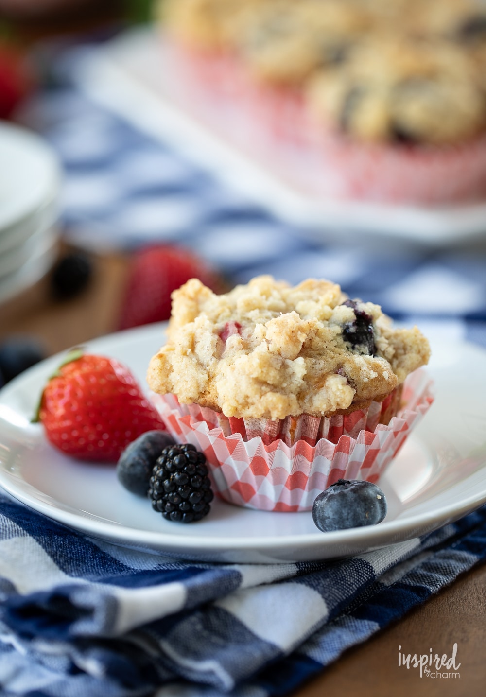 triple berry muffin on a plate with extra berries.