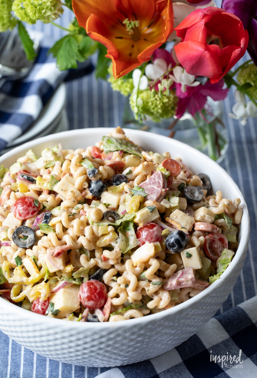 bowl of Italian Sub Pasta Salad with flowers in the background. 