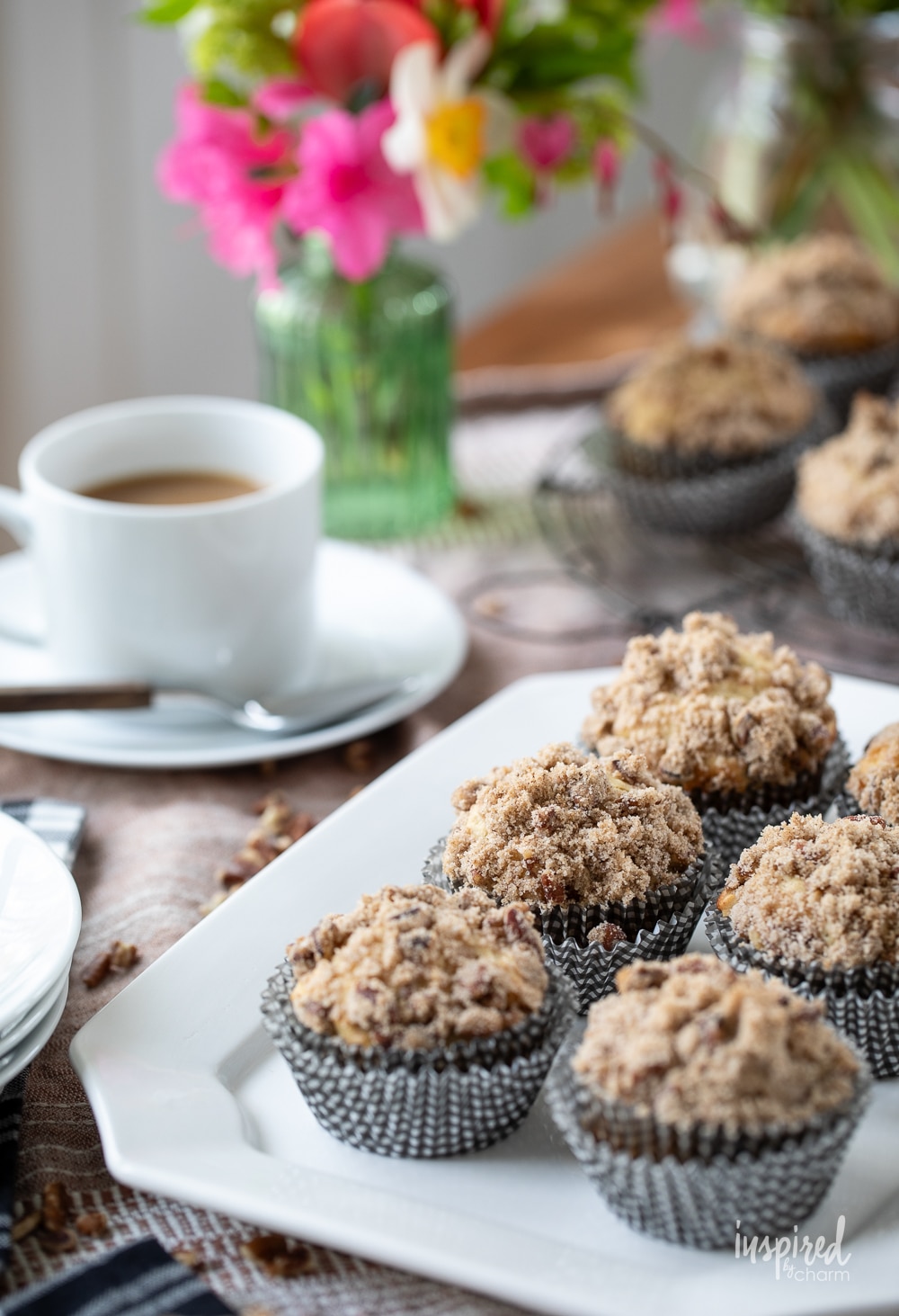 cinnamon maple morning muffin served with a cup of coffee and flowers in the background.