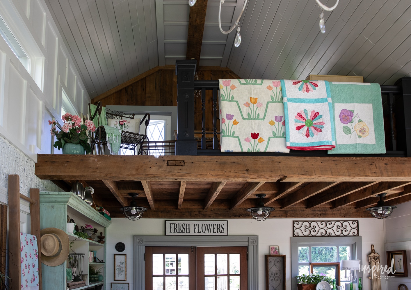 vintage quilts hung on railing around a loft.