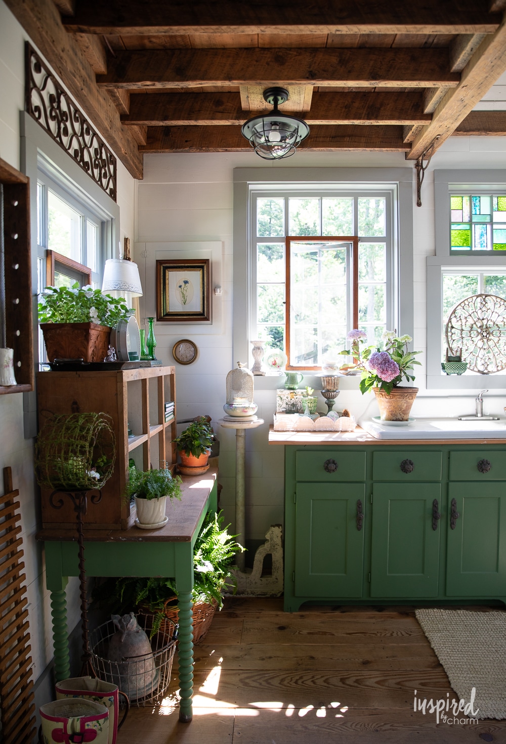 green cabinets and a table in a house decorated with garden and vintage decor.