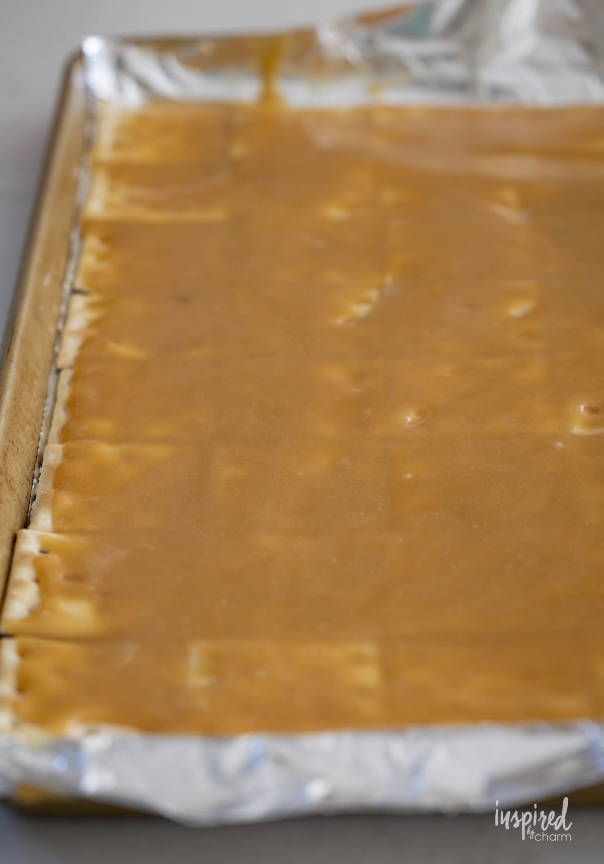 ritz crackers with toffee on a baking sheet.