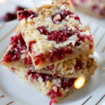 Cranberry Macadamia Coconut Bars stacked on a small plate.