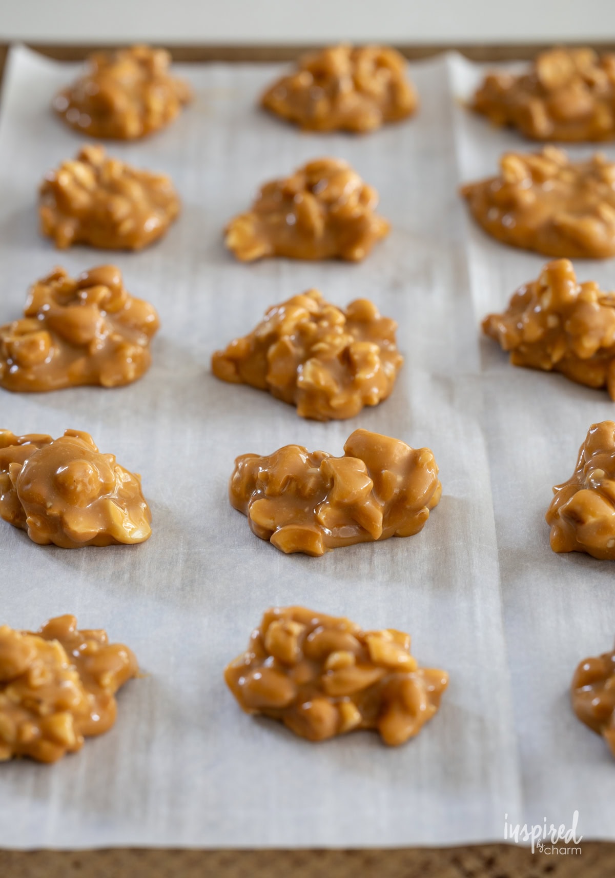caramel and cashew clusters on parchment paper on a baking sheet.