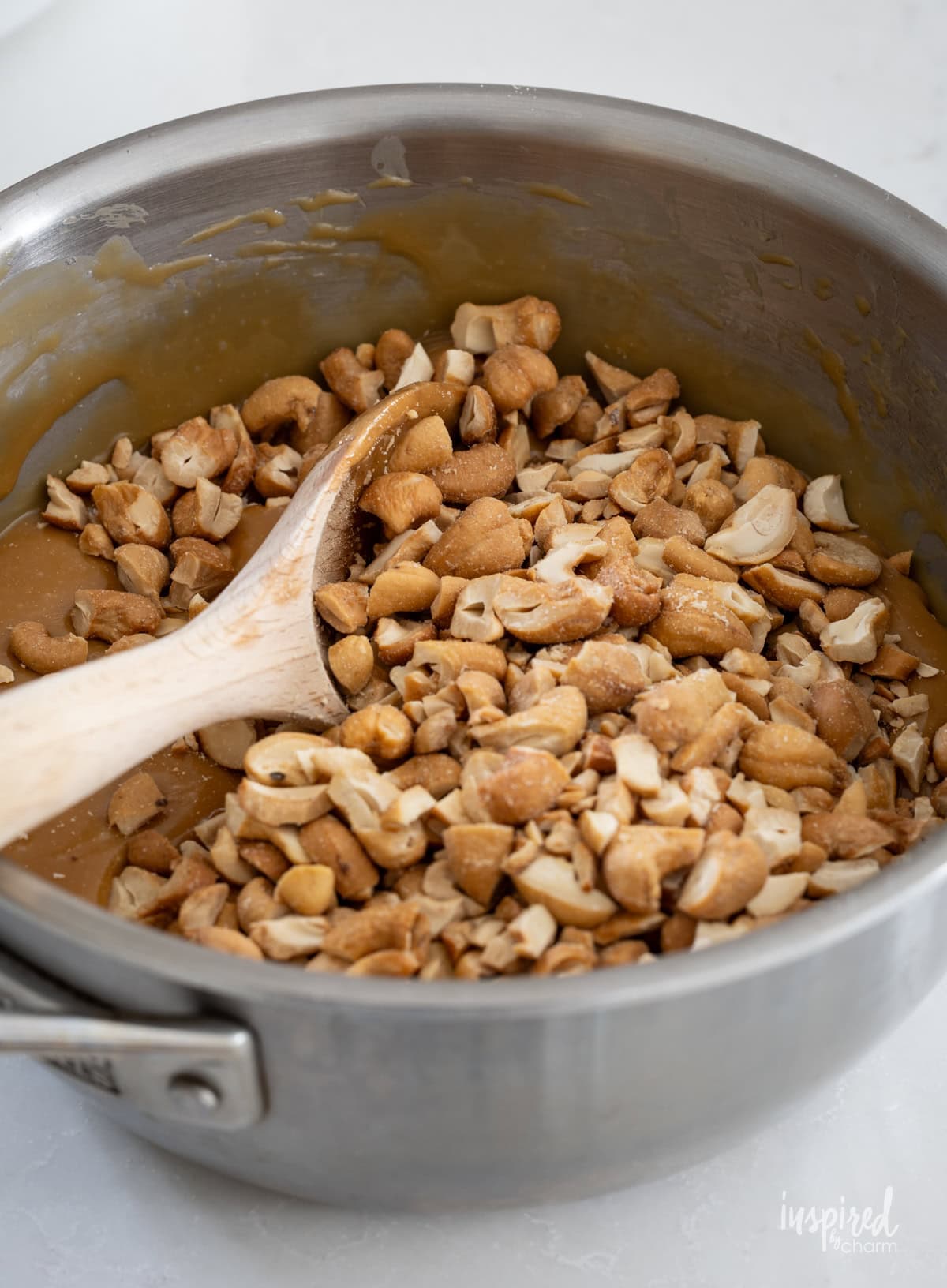 ingredients for Homemade Caramel Cashew Clusters in a pot with spoon.