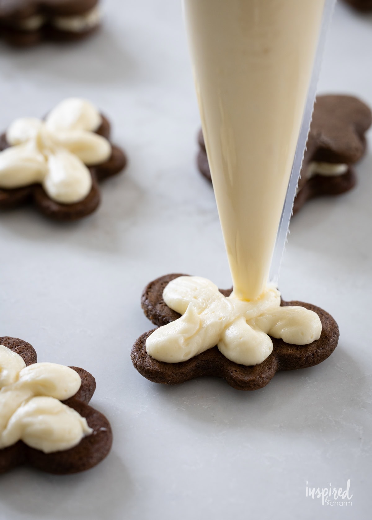 piping bag with buttercream frosting filling a cookie.