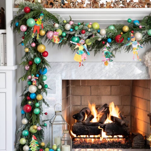 Painted Paper Plate Articulated Christmas Figures hung as a garland on a mantel.