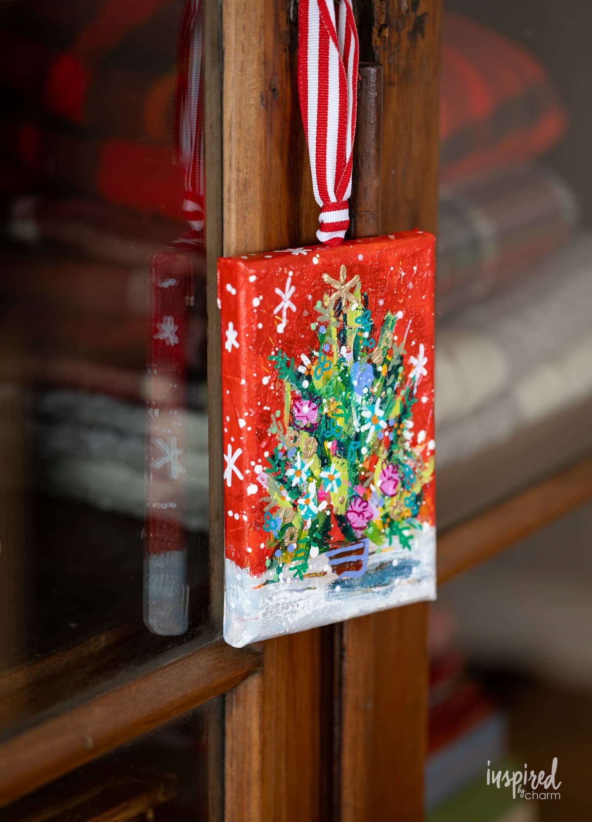 christmas tree painting hung on cabinet.