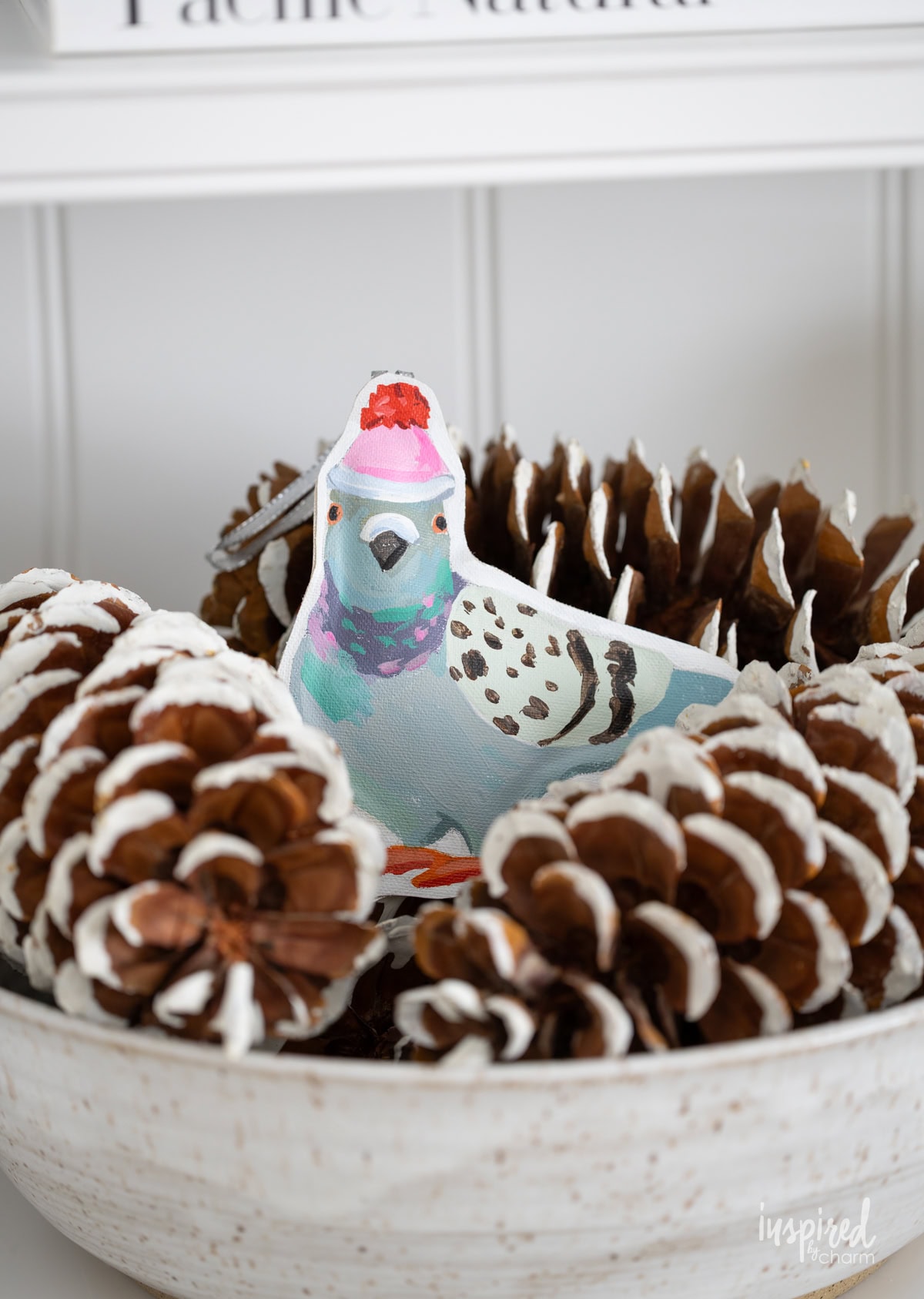 hand painted pigeon ornament in a bowl of pinecones. 
