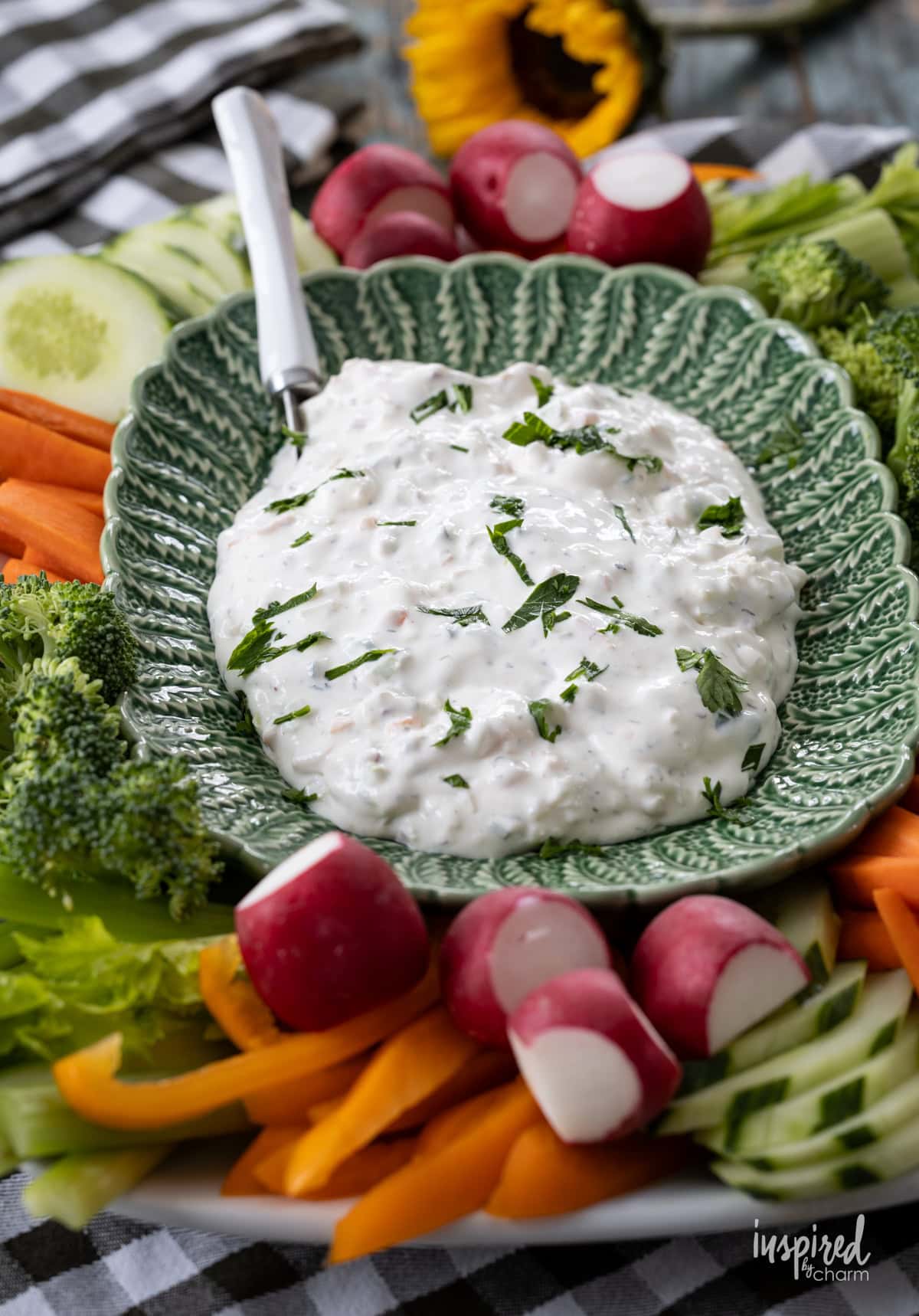 large green bowl filled with creamy garden vegetable dip and lots of vegetables around it. 