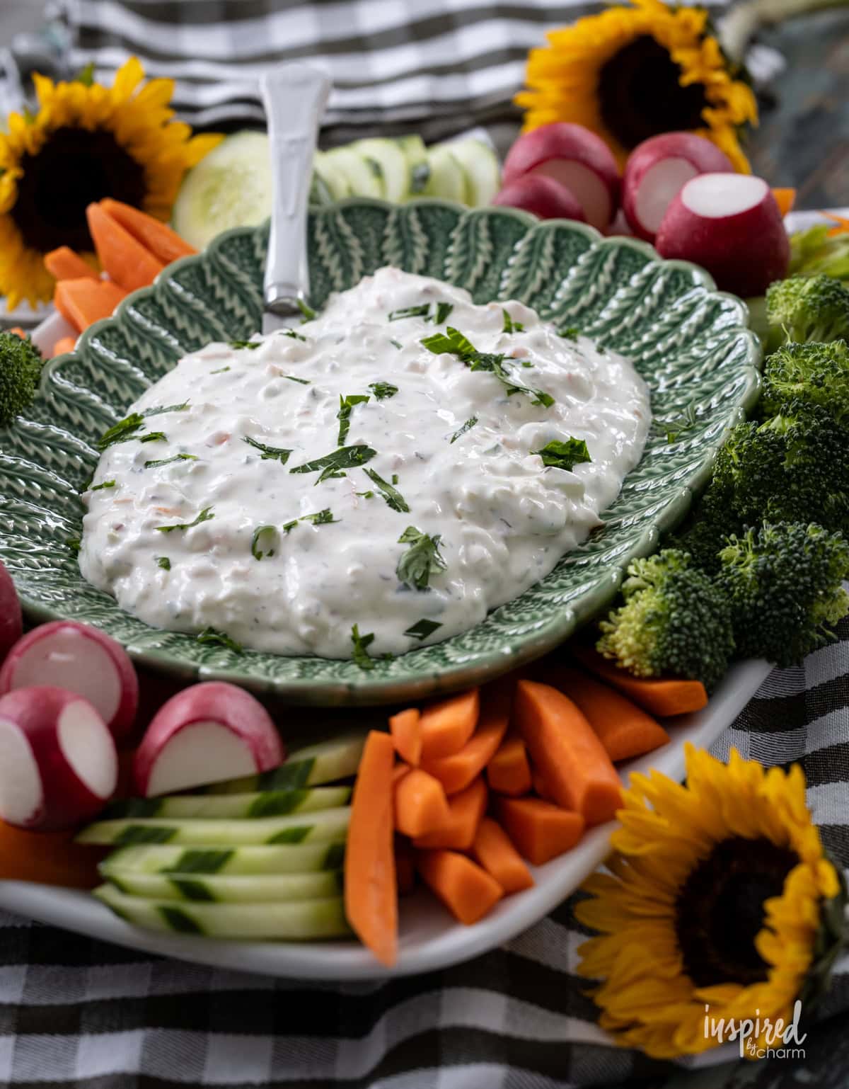 creamy garden vegetable dip in a green bowl with vegetables.