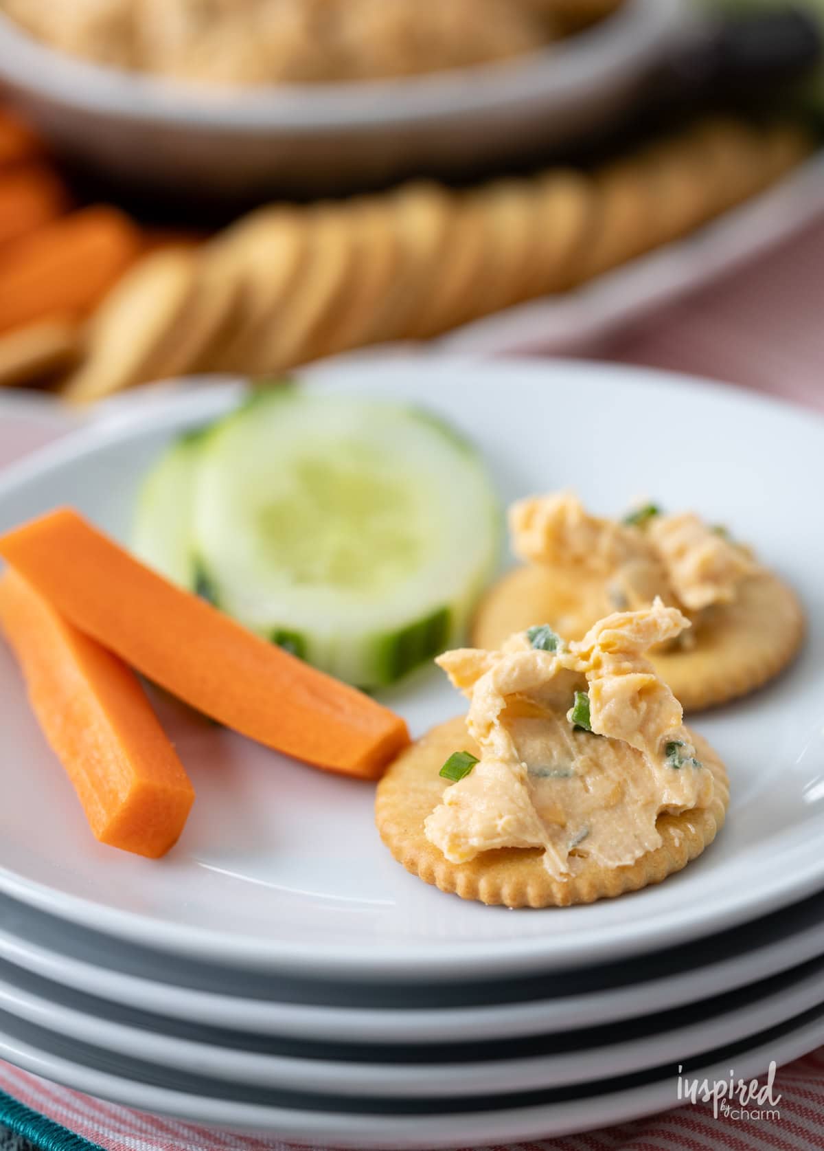 small plates stacked together with cheese on crackers and veggies.