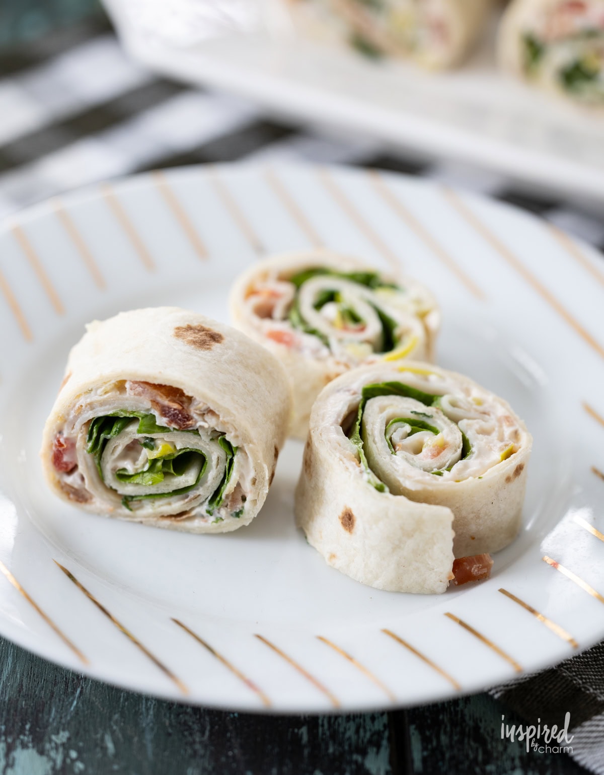 three Turkey Club Sandwich Roll-Ups on a plate.