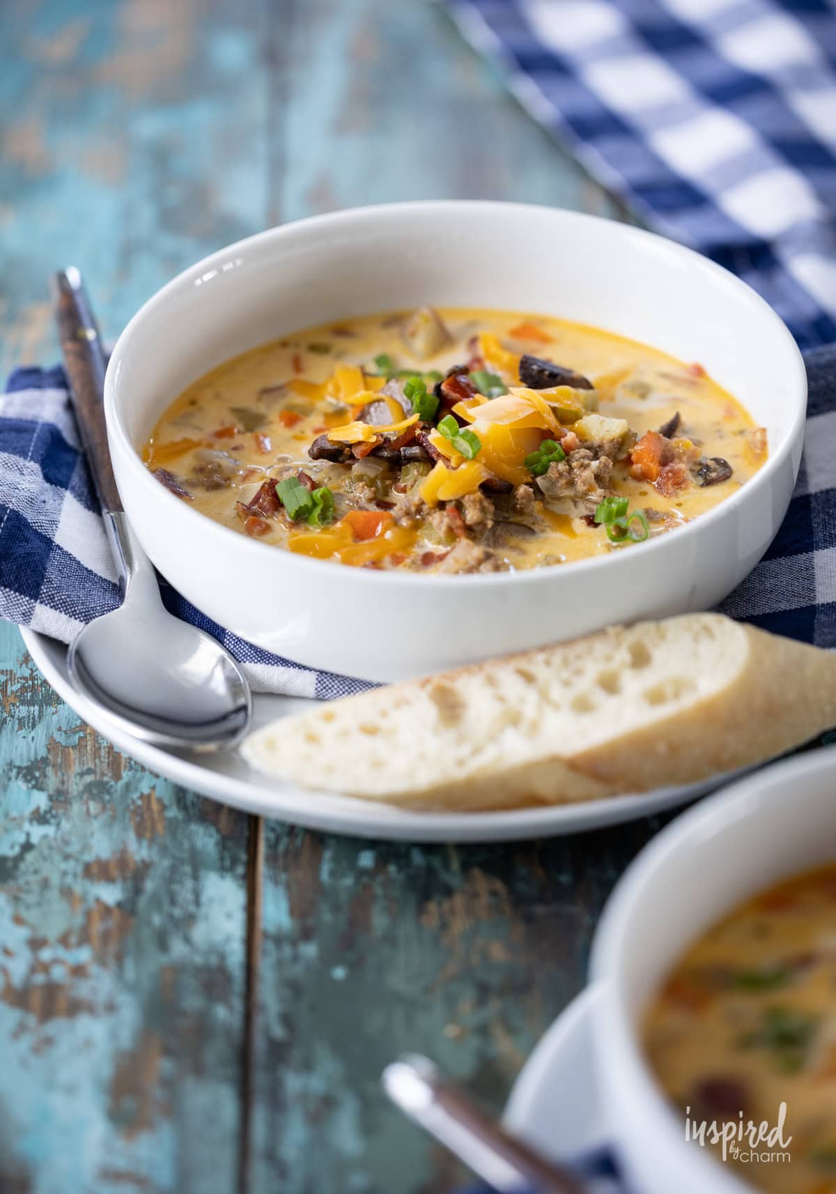 cheeseburger soup in a bowl with a spoon and a piece of bread.