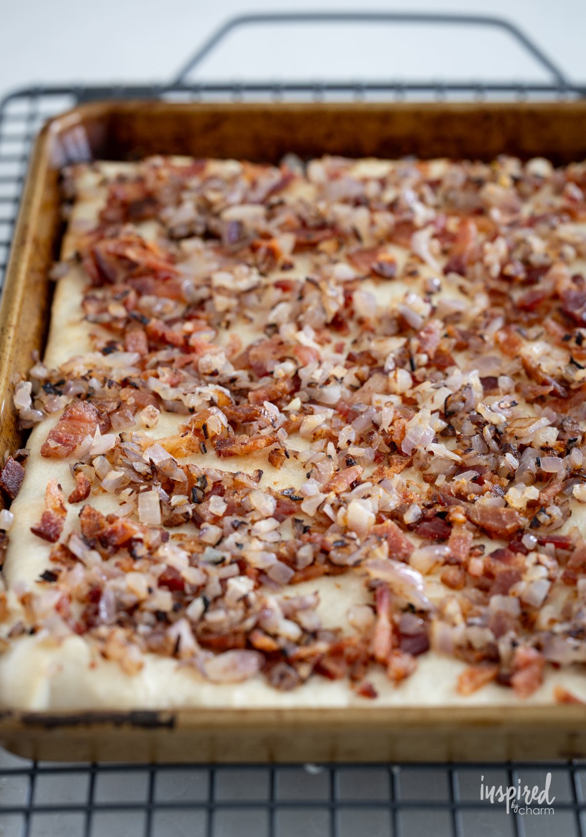 baked pizza crust with bacon and onions in a sheet pan.