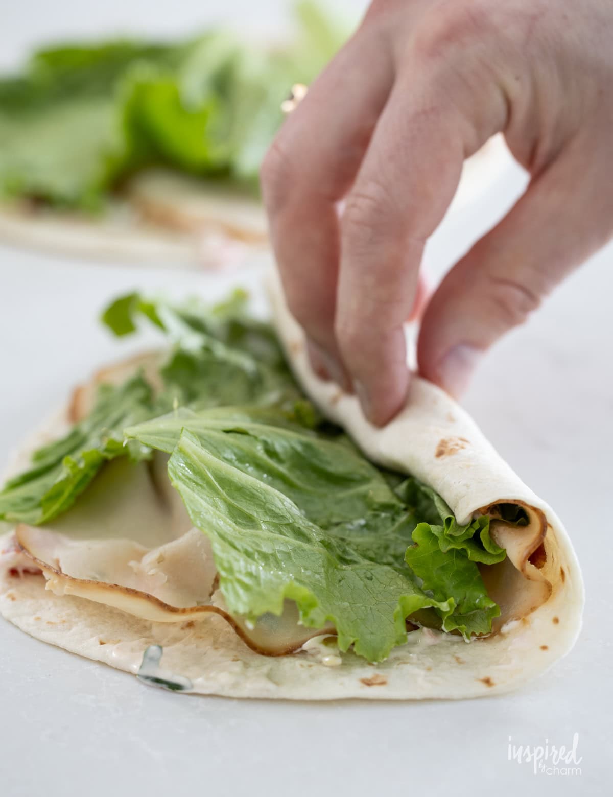 hand rolling up Turkey Club Sandwich in tortilla.
