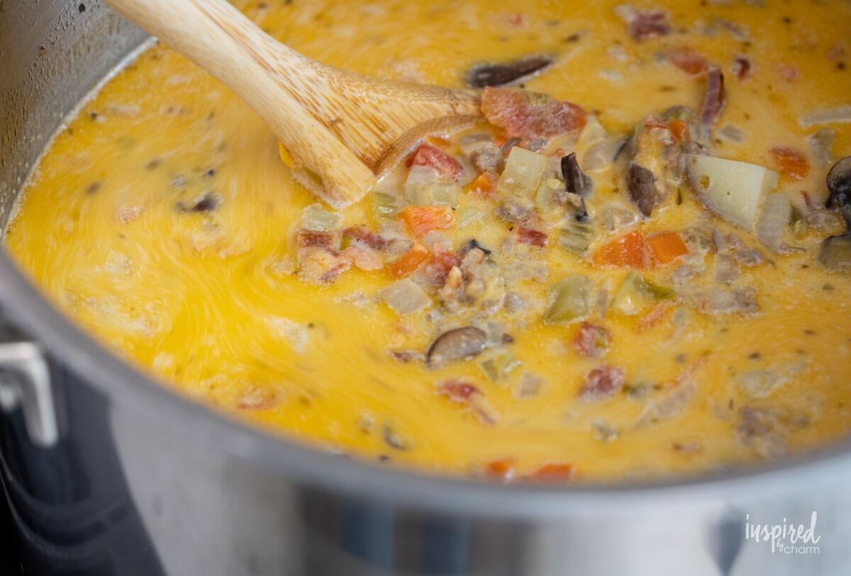 wooden spoon stirring cheeseburger soup on a pot. 