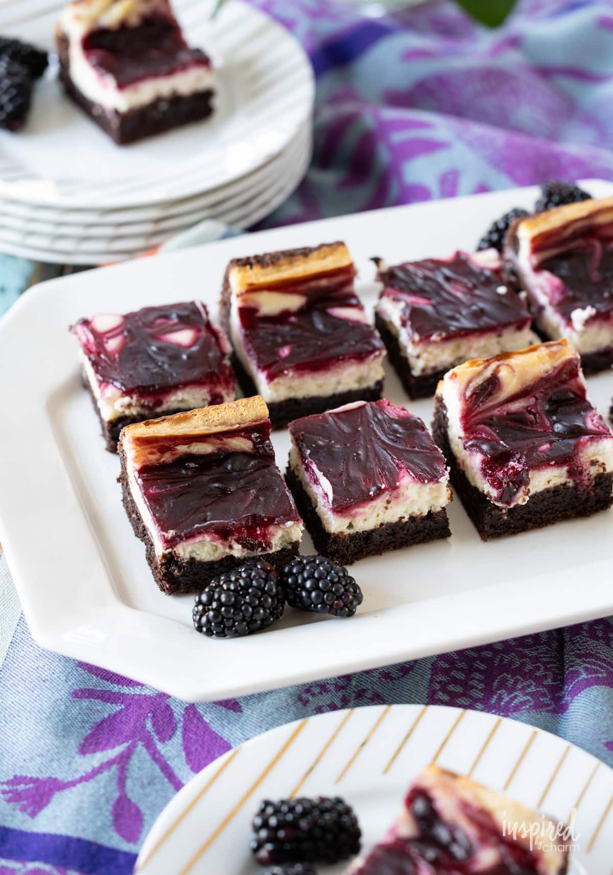 Blackberry Cheesecake Brownies on a platter and served on plates.