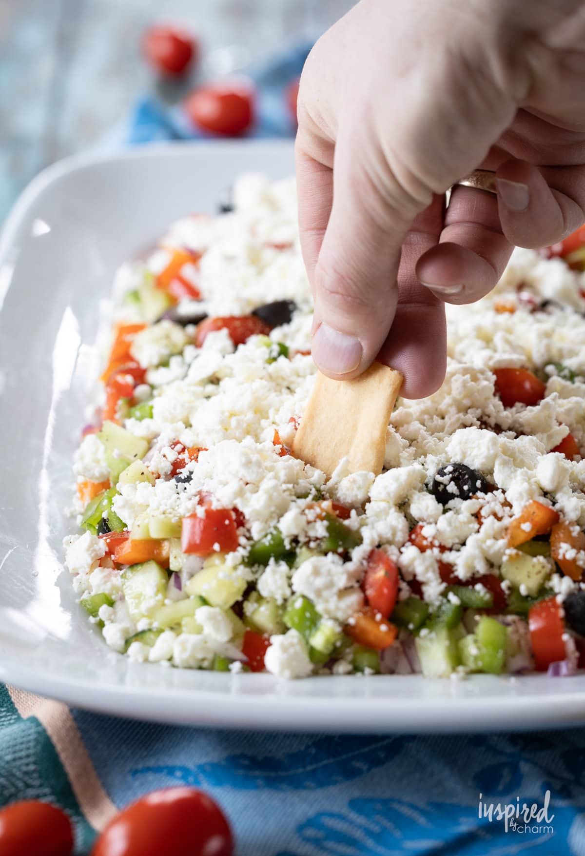 hand with chip taking a dip into greek feta layer dip.