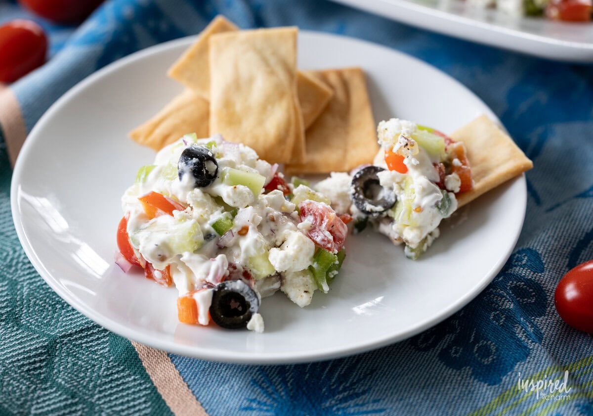 greek feta Layer dip served with pita chips on a small plate.