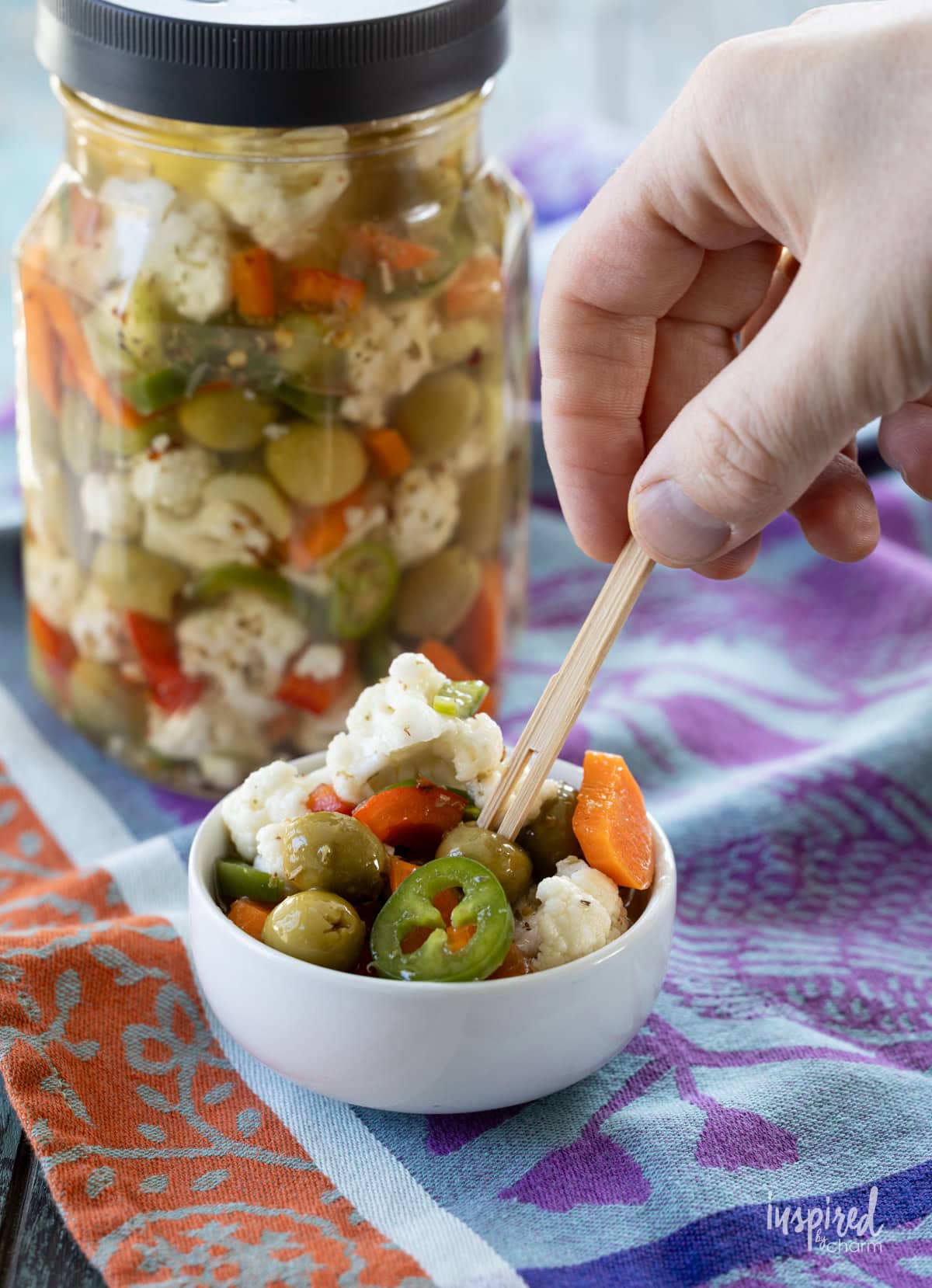 hand with a toothpick taking a bite of  Giardiniera.
