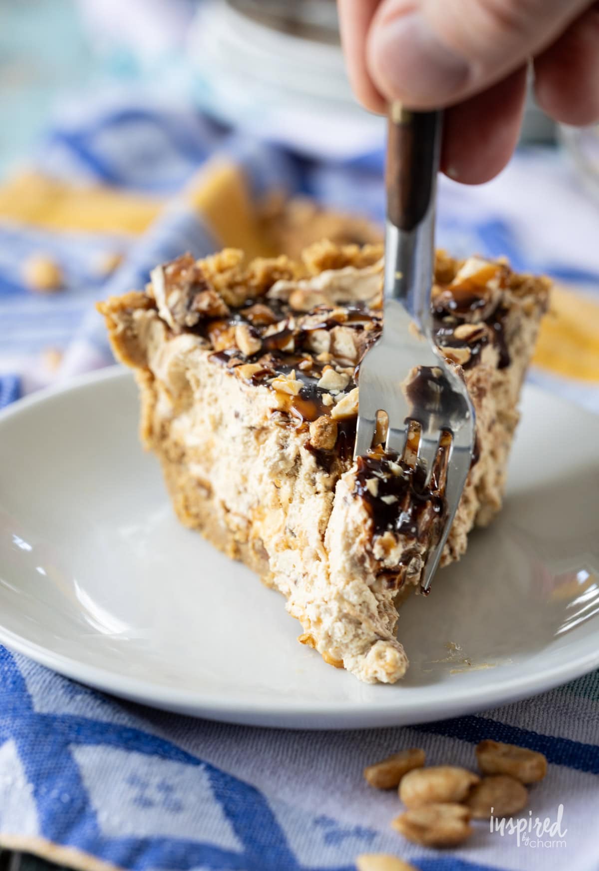 hand with a fork taking bite of Peanut Butter Snickers Pie.