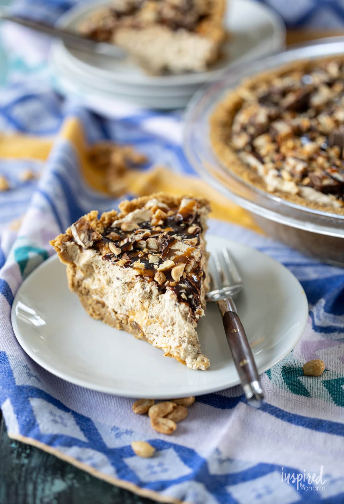 Peanut Butter Snickers Pie on a table with a slice served on a plate.