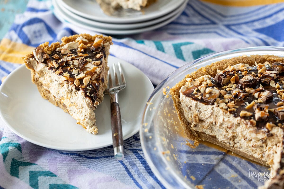 slice of Peanut Butter Snickers Pie on a plate and in a dish dish.
