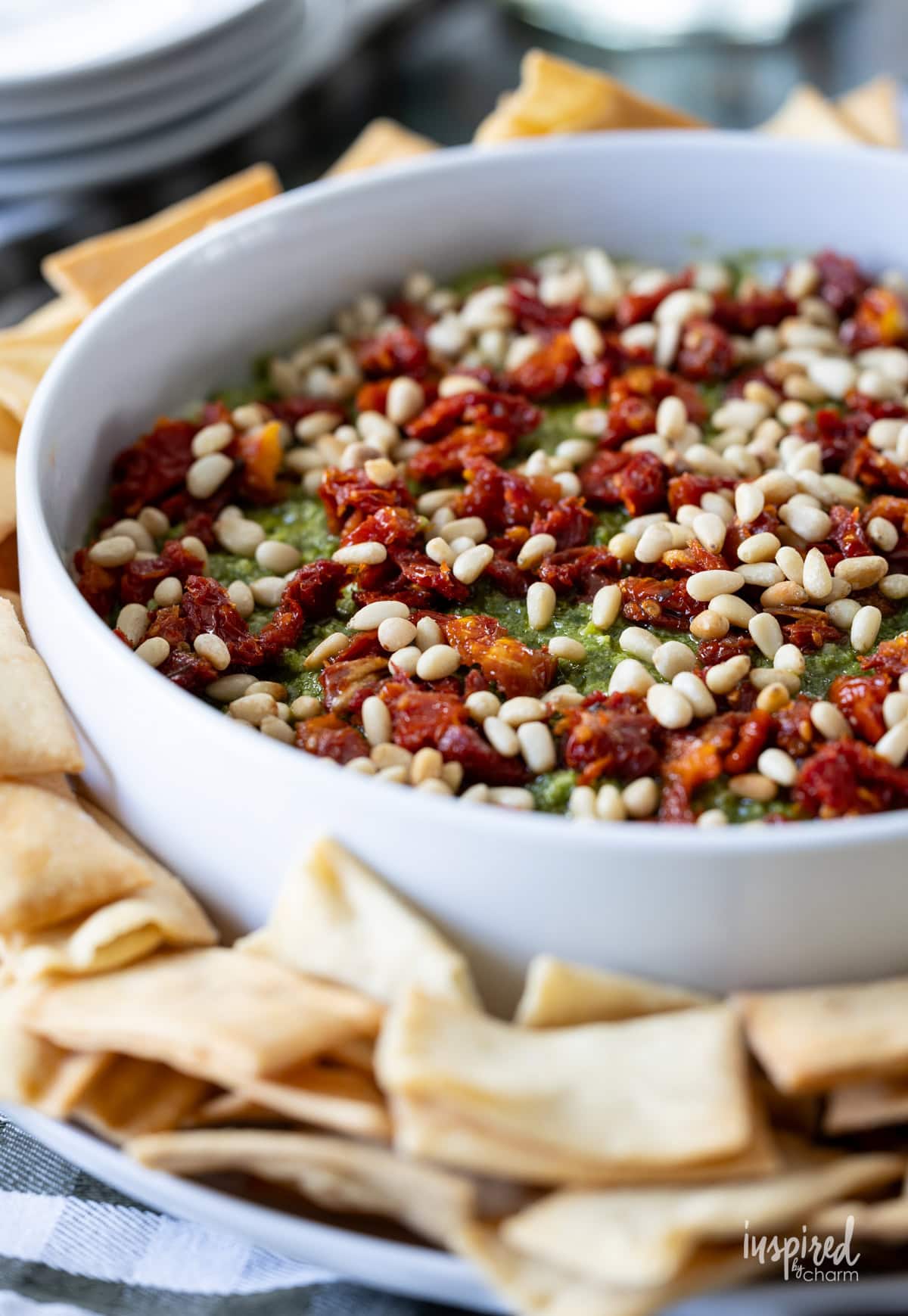 Pesto and Feta Layer Dip in a white round dish with pita chips.