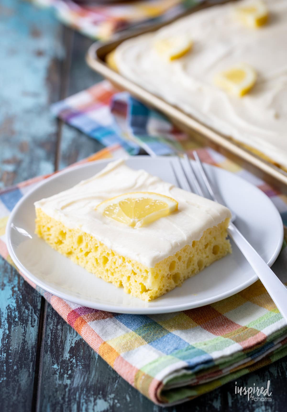 slice of lemon sheet cake on a plate with a fork.