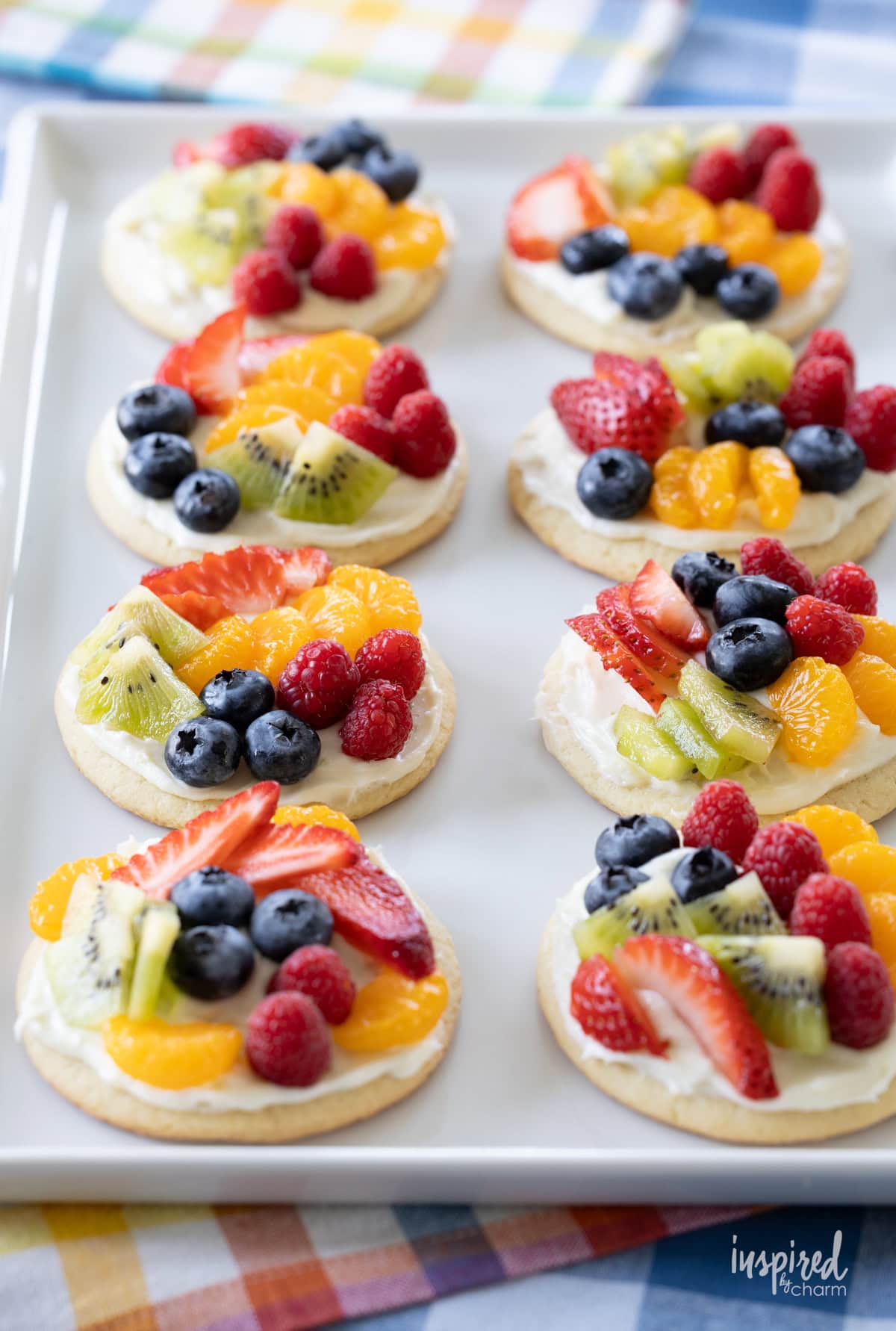 eight mini fruit pizzas in rows on a white plate.