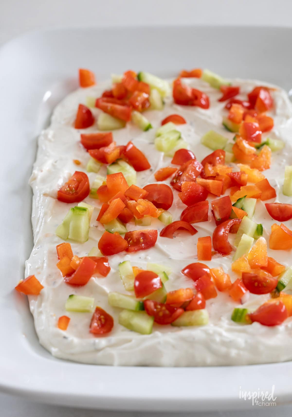 layering greek feta layer dip with vegetables.