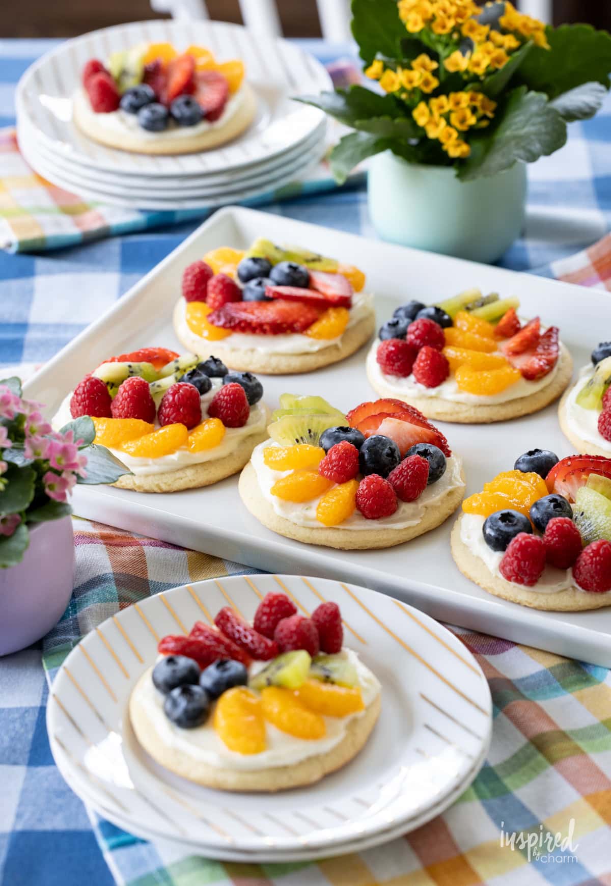 table set with mini fruit pizza on small plates and served on a large platter.