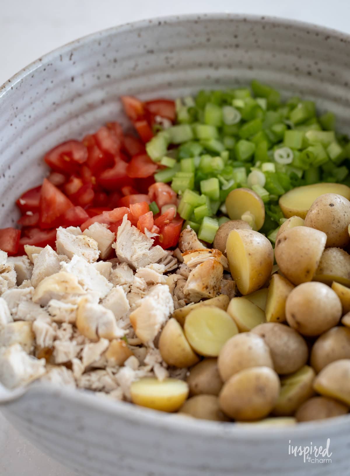 bowl with ingredients for Pesto Chicken Potato Salad.