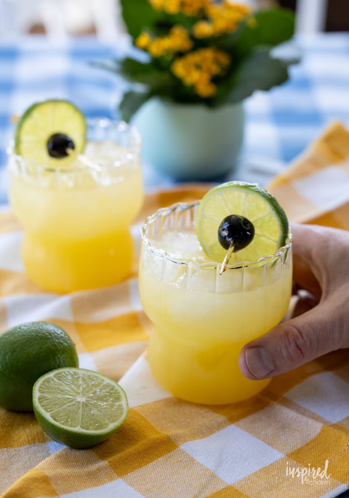 hand holding Black Eyed Susan Cocktail with another in the background.