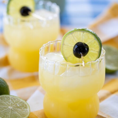 two Black Eyed Susan Cocktails in glasses on a table.