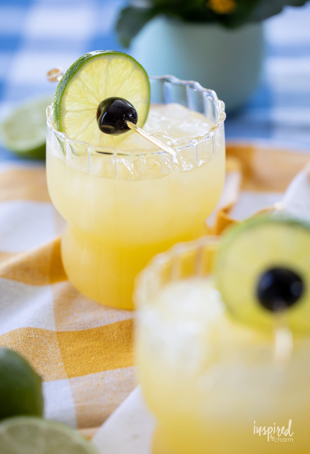two Black Eyed Susan Cocktails on a table with napkins and tablecloth.