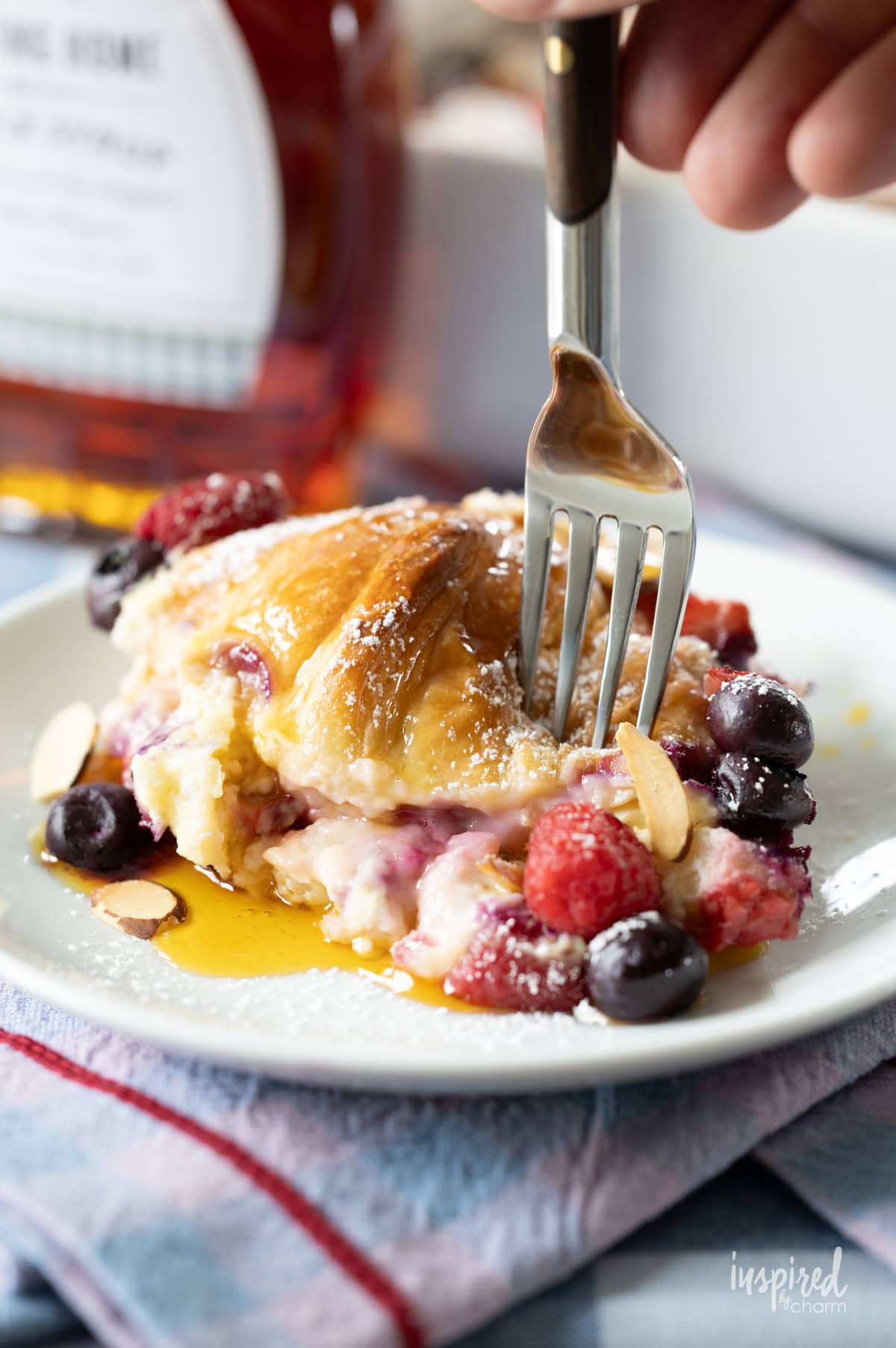 fork taking a bite of Mixed Berry Croissant Breakfast Casserole on a plate.