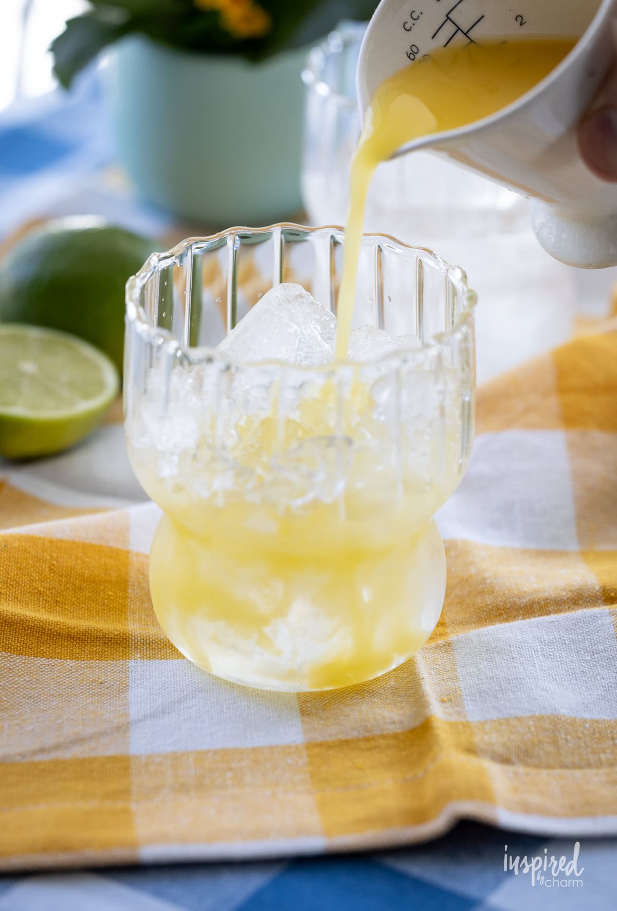 jigger pouring juice into a rocks glass with ice.