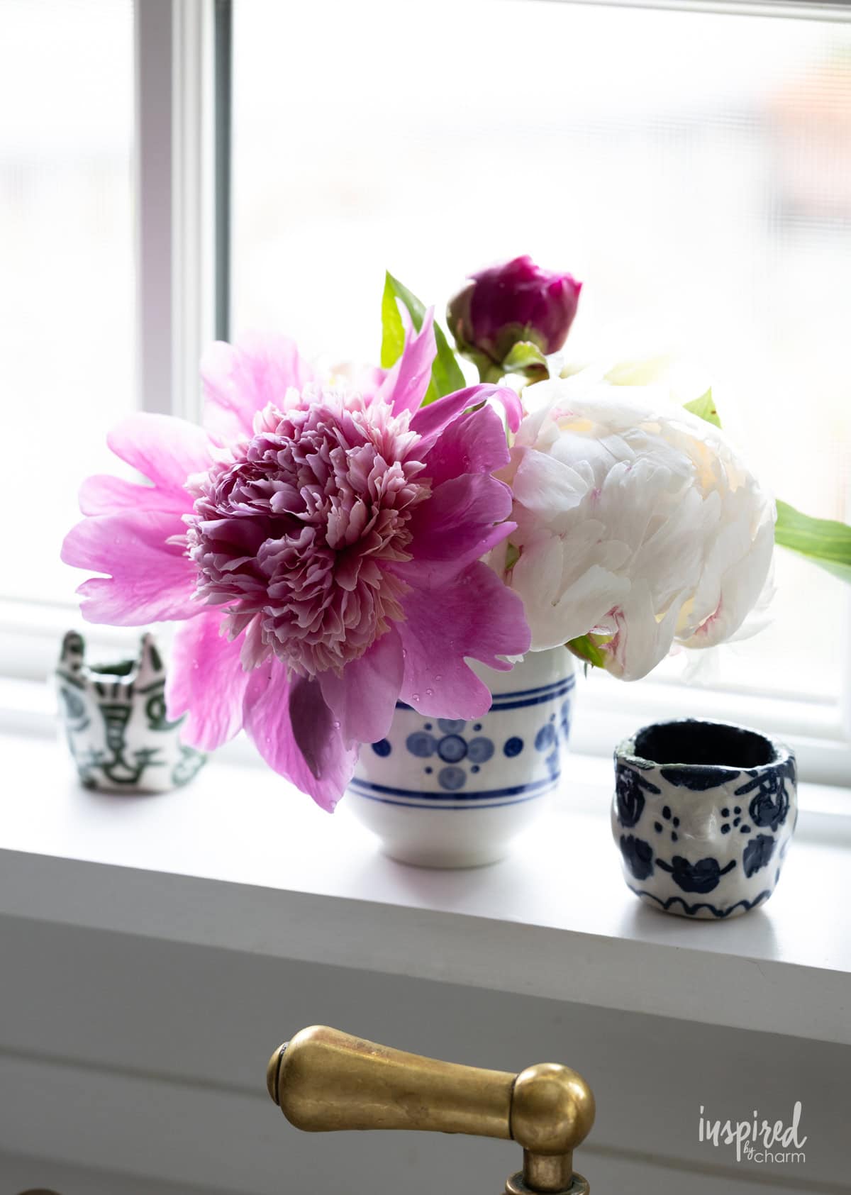 peonies in small white and blue cup. 