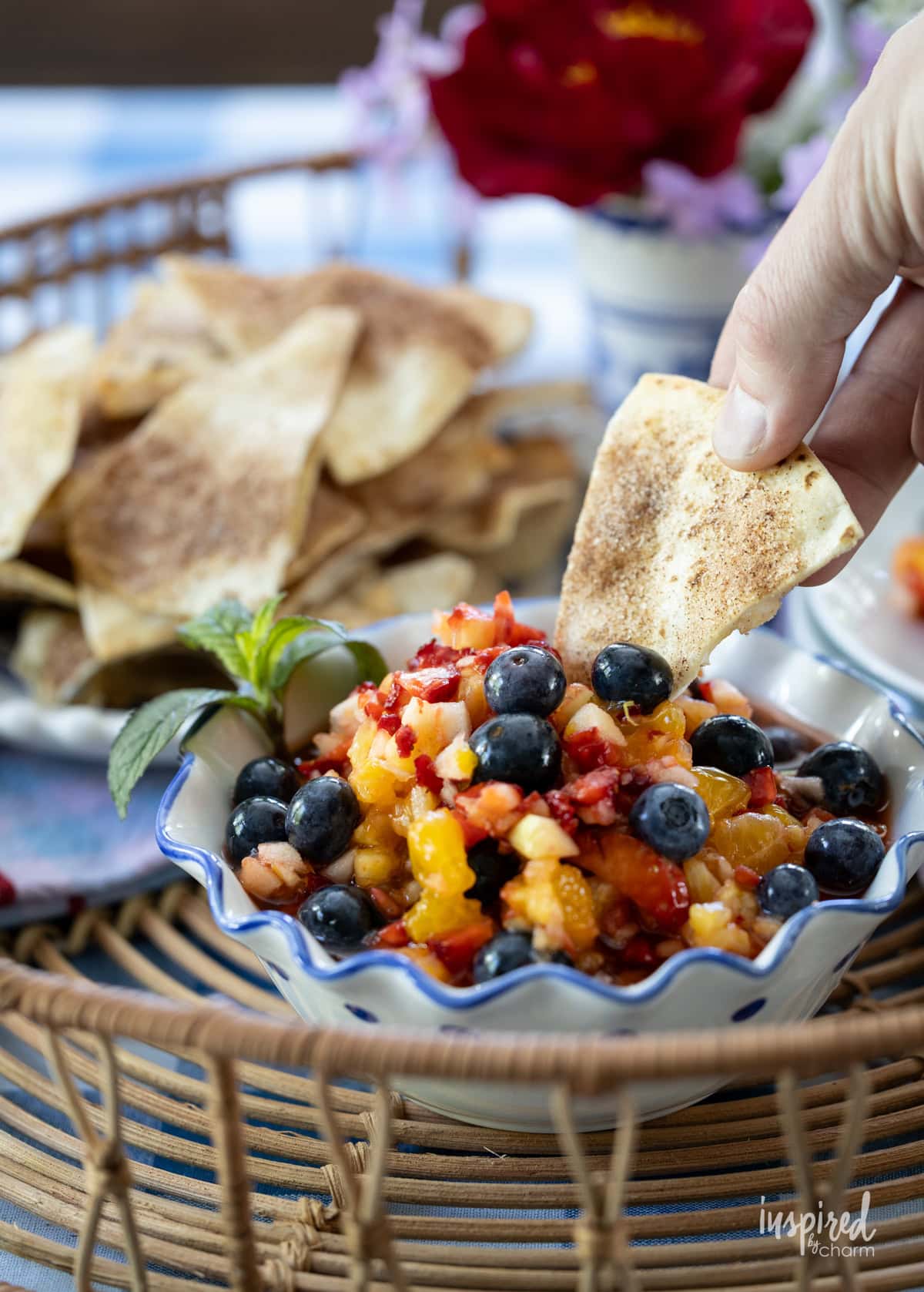 hand with tortilla chips dipping into fruit salsa.