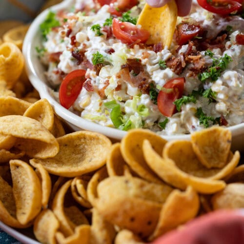 hand with a frito scoop taking a bite of BLT Corn Dip.